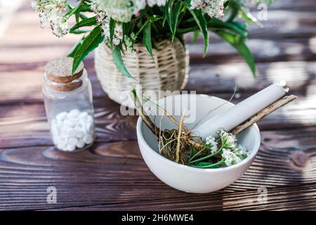 Baldrian-Tabletten mit beruhigenden Eigenschaften. Pharmazeutisches Glas mit Pillen auf einem Holztisch. Kochen Baldrianwurzel in einem Mörser für Kräuterelixiere. S Stockfoto