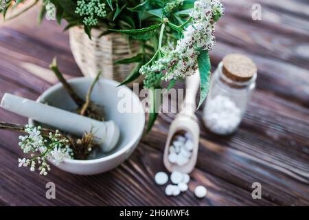 Baldrian-Tabletten mit beruhigenden Eigenschaften. Pharmazeutisches Glas mit Pillen auf einem Holztisch. Kochen Baldrianwurzel in einem Mörser für Kräuterelixiere. S Stockfoto