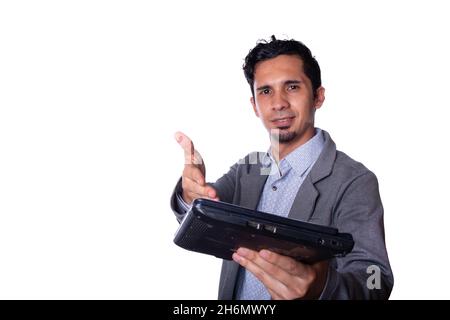 Geschäftsmann zeigt und übergibt einen Laptop mit seinen Händen. Junger, erwachsener lateinischer Mann in moderner Business-Kleidung, isoliert auf Weiß Stockfoto