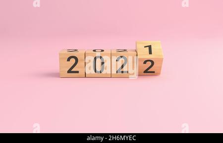 Kipp über Holzwürfelblock 2021 - 2022 frohes neues Jahr auf rosa Hintergrund. 3D-Illustration. Stockfoto