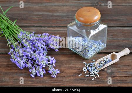 Bouquet von frischem Lavendel in der Nähe von trockenem Lavendel in einem Glas auf einem Holztisch. Stockfoto