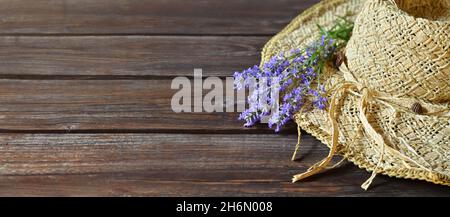Korbhut mit Strauß lila Lavendelblüten auf einem Holztisch mit einem Kopierraum. Sommerkomposition. Stockfoto