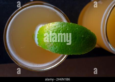 Ein Flug aus klaren Probengläsern, gefüllt mit goldfarbenem mexikanischen Craft-Bier und einer leuchtend grünen Limettenscheibe am Rand des Getränks. Stockfoto