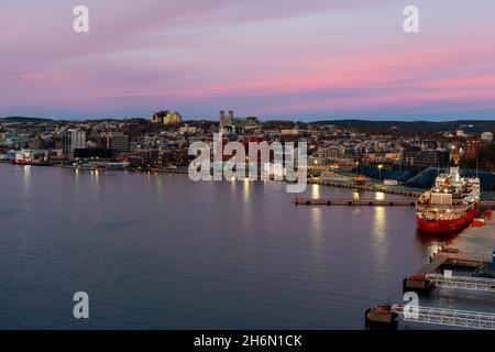 Am Abend überblickte der rosafarbene Himmel den Hafen von St. John mit dem Schiff der kanadischen Küstenwache, Louis St Laurent, und vor Anker liegenden Öl- und Gasversorgungsschiffen. Stockfoto