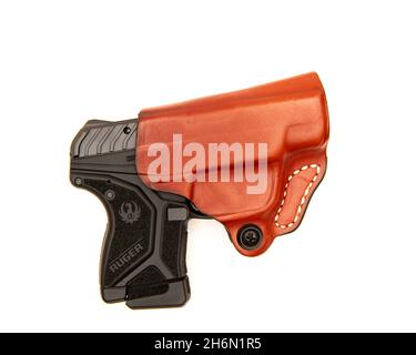 Eine halbautomatische 10-Schuss-Pistole Ruger LCP II im Kaliber .22 LR in einem auf Weiß isolierten Lederholster. Stockfoto