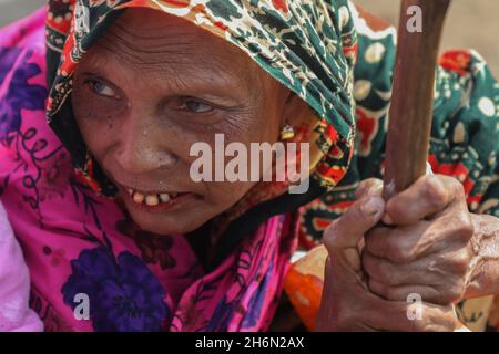 Dhaka, Bangladesch. November 2021. Eine alte Slumbewohnerin sah, wie sie ihren Stock in der Schlange hielt, um sich in einem Korail-Slum-Impfzentrum mit Dosen Oxford-AstraZeneca impfen zu lassen. Die Regierung iminokuliert die Bewohner des Slums Korail, einer der größten Einwohner von einkommensschwachen Menschen in Dhaka. Die Generaldirektion für Gesundheitsdienste (DGHS) wird fast 300,000 Menschen, die im Slum leben, unter das Impfprogramm Covid-19 bringen. Kredit: SOPA Images Limited/Alamy Live Nachrichten Stockfoto