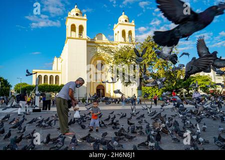 San Salvador, El Salvador. November 2021. Ein Mann und sein Enkel füttern Tauben vor der Kathedrale von San Salvador. Kredit: SOPA Images Limited/Alamy Live Nachrichten Stockfoto