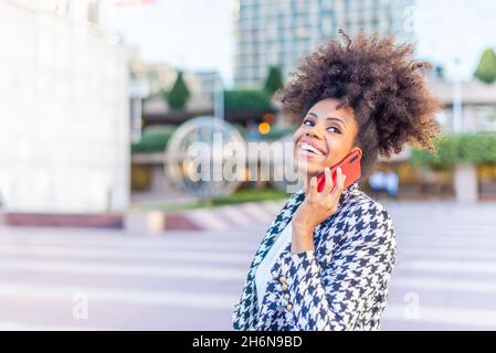Lächelnde Geschäftsfrau, die in der Stadt telefoniert Stockfoto