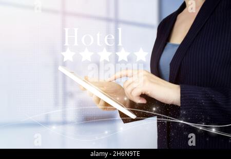 Customer Experience Konzept. Weißes Tablet mit Handberührung und digitalem Hologramm, fünf-Sterne-Schild mit Hoteltext auf hellem, unscharfem Hintergrund. Überprüfung, Bewertung Stockfoto