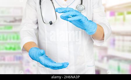 Ärztin, die etwas in ihrer Hand zeigt. Arzt leere Handfläche in medizinischen Handschuhen. Medizinisches Fachpersonal, das ein virtuelles Objekt mit Händen hält Stockfoto