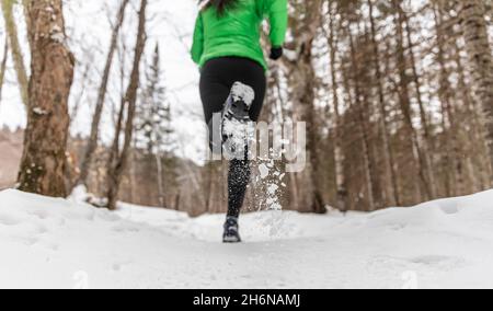 Winter Laufen in schneit Wald Natur. Frau Läuferpfad läuft im Schnee in der Winterwaldlandschaft. Weibliche Langlauferin läuft in warmer Kleidung Stockfoto