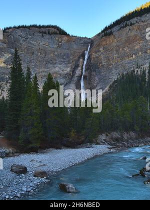 Atemberaubende Aussicht auf den majestätischen Wasserfall Takakkaw Falls im Yoho National Park, British Columbia, Kanada am Abend mit wildem Fluss und Wald. Stockfoto