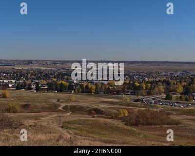 Wunderschöner Blick über den beliebten Nose Hill Park im Norden von Calgary, Alberta, Kanada, im Herbst mit farbenfrohem Gras und Büschen und einem Wohngebiet. Stockfoto