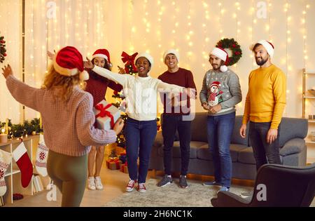 Eine Gruppe von Freunden in santa Hats begrüßen ihre Freundin auf der Weihnachtsfeier zu Hause. Stockfoto
