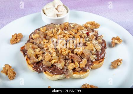Belgische Waffeln mit Kastanien und Eis auf einem weißen Teller. Waffeln aus Schokolade, Kastanien und Nussbaum. Stockfoto
