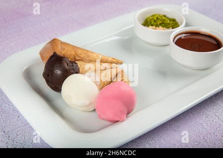 Buntes Eis in einem kleinen Kegel. Vier verschiedene Geschmacksrichtungen von Eiszapfen: Schokolade, Karamell, Vanille und Erdbeere. Stockfoto