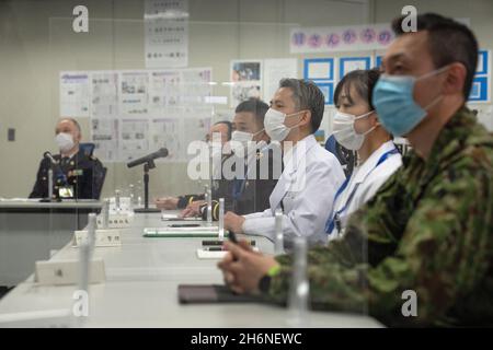 Tokio, Japan. November 2021. Ziviles und militärisches medizinisches Personal sitzt zwischen schützenden Kunststoffteilern, während sie am 17. November 2021 in einem Coronavirus-Massenimpfzentrum in Tokio, Japan, an einer Einweisung teilnehmen. Die japanische Regierung hat angekündigt, ab dem 1. Dezember mit der Verabreichung von Covid-19-Impfstoffverstärkungen zu beginnen, nachdem der Schritt Anfang dieser Woche genehmigt wurde. (Bild: © POOL via ZUMA Press Wire) Stockfoto