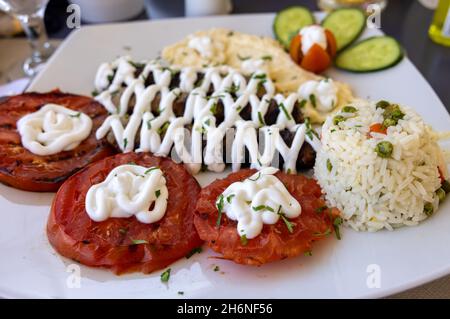 Gebratene Souvlaki und gegrillte Tomaten. Typisch leckeres griechisches Mittagessen Stockfoto