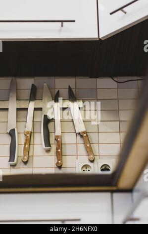 POZNAN, POLEN - 09. Jun 2018: Eine vertikale Aufnahme scharfer Küchenmesser, die an einem Wandmagneten hängen, Poznan, Polen Stockfoto