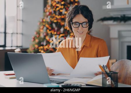 Lächelnde hispanische Angestellte, die während der weihnachtszeit im Büro arbeitet Stockfoto