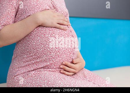 Nahaufnahme eines Schwangeren, der die Hände an einer Babybumper in einem medizinischen Schrank hält. Frau mit Schwangerschaft erwartet Kind und Vorbereitung auf die Geburt. Person mit Baby im Mutterleib bei Konsultation Stockfoto