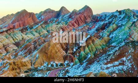 Zhangye, Zhangye, China. November 2021. Am 15. November 2021 ist der Winter die Zeit für die farbenfrohe Danxia in Zhangye, Gansu, sich zu "ändern". Der weiße Schnee bedeckt sanft die verblassende Landschaft unter der untergehenden Sonne. Die Wolken und der Nebel über Danxia geben einem das Gefühl, darin zu gehen. In eine traumhafte Welt. Der Zhangye Danxia Geopark ist ein umfassender Geopark mit der landschaftlichen Landschaft von Danxia und der farbenfrohen hügeligen Landschaft als Hauptkörper, der geologische Relikte wie stratigraphische Profillandschaft, strukturelle Profillandschaft und farbenfrohe hügelige landschaftliche Landschaft integriert. Seine Danxia-Landform i Stockfoto