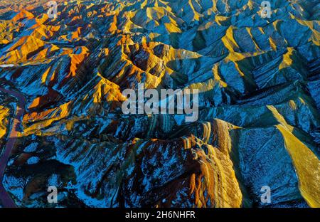 Zhangye, Zhangye, China. November 2021. Am 15. November 2021 ist der Winter die Zeit für die farbenfrohe Danxia in Zhangye, Gansu, sich zu "ändern". Der weiße Schnee bedeckt sanft die verblassende Landschaft unter der untergehenden Sonne. Die Wolken und der Nebel über Danxia geben einem das Gefühl, darin zu gehen. In eine traumhafte Welt. Der Zhangye Danxia Geopark ist ein umfassender Geopark mit der landschaftlichen Landschaft von Danxia und der farbenfrohen hügeligen Landschaft als Hauptkörper, der geologische Relikte wie stratigraphische Profillandschaft, strukturelle Profillandschaft und farbenfrohe hügelige landschaftliche Landschaft integriert. Seine Danxia-Landform i Stockfoto