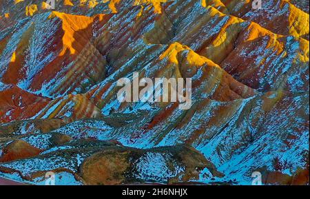 Zhangye, Zhangye, China. November 2021. Am 15. November 2021 ist der Winter die Zeit für die farbenfrohe Danxia in Zhangye, Gansu, sich zu "ändern". Der weiße Schnee bedeckt sanft die verblassende Landschaft unter der untergehenden Sonne. Die Wolken und der Nebel über Danxia geben einem das Gefühl, darin zu gehen. In eine traumhafte Welt. Der Zhangye Danxia Geopark ist ein umfassender Geopark mit der landschaftlichen Landschaft von Danxia und der farbenfrohen hügeligen Landschaft als Hauptkörper, der geologische Relikte wie stratigraphische Profillandschaft, strukturelle Profillandschaft und farbenfrohe hügelige landschaftliche Landschaft integriert. Seine Danxia-Landform i Stockfoto