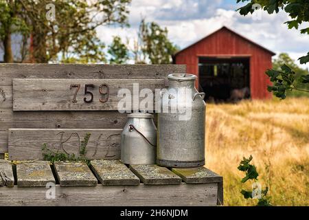 Zwei Milchdosen vor einer Farm, bereit zur Abholung, Gotland, Schweden Stockfoto