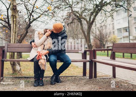 Liebevoller Ehemann unterstützt Frau Umarmung im Freien im Herbst Park. Traurige depressive Frau weint und bedeckt das Gesicht mit der Hand. Carering Mann hilft und tröstet Stockfoto