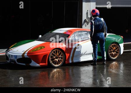 Der Rennfahrer sieht den Ferrari F430 im Design der italienischen Nationalflagge vor der Boxengasse in der Boxengasse bei Regen, Circuit de Stockfoto