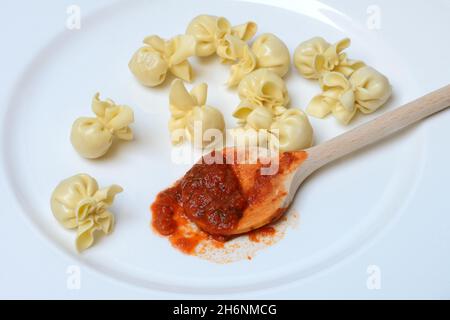 Saccottini, italienische Pasta auf dem Teller und Kochlöffel mit Tomatensauce, Pasta Stockfoto