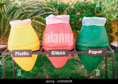 Drei Abfallbehälter für das Recycling. Sortierung von Schutt - Kunststoff, Glas und Papier. Nahaufnahme von bunten Töpfen, die als Müllcontainer verwendet werden. Das ist sehr wichtig Stockfoto