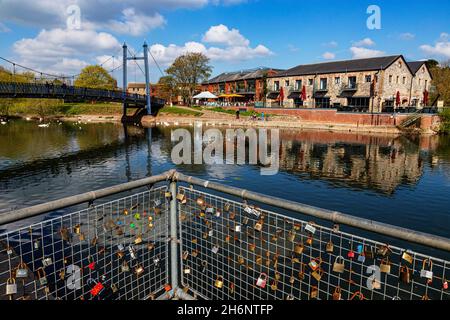 Detail von ‘Love-Locks’ Padlocks & Cricklepit Suspension Bridge over the River exe mit Riverside Restaurants und Gebäuden, Blue Sky und Swans; Exeter Stockfoto