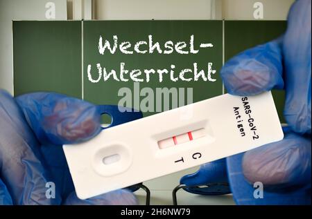 FOTOMONTAGE, positiver Antigen-Schnelltest, Tafel mit Aufschrift WECHSELUNTERRICHT, Klassenzimmer, Corona-Krise, Deutschland Stockfoto