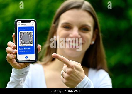 Symbol Foto Impfprivilegien, junge Frau mit App CovPass auf dem Smartphone mit digitalem europäischen Impfpass inklusive QR-Code Stockfoto