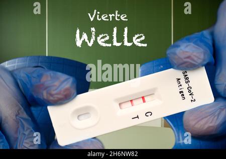 FOTOMONTAGE, positiver Antigenschnelltest, Tafel mit Aufschrift VIERTE WELLE, Klassenzimmer, Corona-Krise, Deutschland Stockfoto
