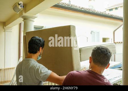 MAILAND, ITALIEN - 30. Sep 2021: Zwei Männer, die Holzregale während ihres Wohnumzugs in Mailand, Italien, umziehen Stockfoto