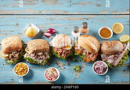 Draufsicht Zusammensetzung von appetitlichen deutschen Seafood Sandwiches mit verschiedenen Arten von Brötchen und gefüllt mit Fisch und Garnelen auf verwittertem Holzbac Stockfoto