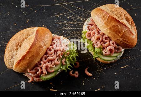 Von oben traditionelle deutsche Fast-Food-Sandwiches mit knusprigen Brötchen gefüllt mit nordseenkrabben mit geschnittenen frischen Gurken und Salatblättern Stockfoto