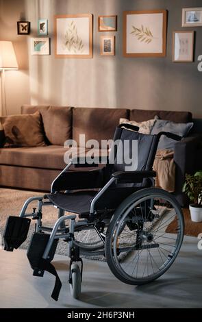 Bild eines leeren Rollstuhls, der zu Hause im Wohnzimmer steht Stockfoto
