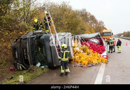 Talkau, Deutschland. November 2021. Rettungsdienste stehen auf und in der Nähe eines umgedrehten Getränkehauses am Unfallort auf der Autobahn A24. Der Lastwagen hatte die Fahrbahn am Morgen verlassen und umgestrostet, wobei er seine Last auf die Fahrbahn streute. (To dpa 'Truck loaded with crates of drinks overturns on motorway') Quelle: Daniel Bockwoldt/dpa/Alamy Live News Stockfoto