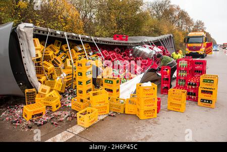 Talkau, Deutschland. November 2021. Männer stapeln Getränkekisten von der Rückseite eines umgedrehten Lastwagens am Unfallort auf der Autobahn A24. Der Lastwagen hatte die Fahrbahn am Morgen verlassen und umgestrostet, wobei die Last auf der Fahrbahn verteilt wurde. (To dpa 'Truck loaded with crates of drinks overturns on motorway') Quelle: Daniel Bockwoldt/dpa/Alamy Live News Stockfoto