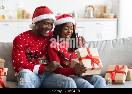 Fröhliche schwarze Liebhaber Austausch Weihnachtsgeschenke, häusliche Innenausstattung Stockfoto