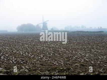 Frisch gepflügtes Feld und Silhouette der Windmühle in den niederlanden im Herbst Stockfoto