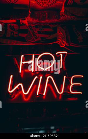 Neonzeichen „ heißer Wein “. Leuchtendes rotes Neonschild im Café-Interieur Stockfoto