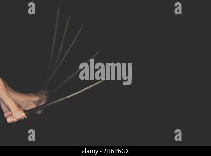 Männliche Hände halten ein Katana auf einem schwarzen Hintergrund. Ein Kendo-Krieger mit Shinai-Schlägen. Platz für Text. Mockup-Banner. Stockfoto