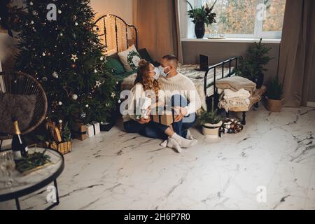 Küssen Paar in Gesichtsmasken mit Geschenken. Stockfoto