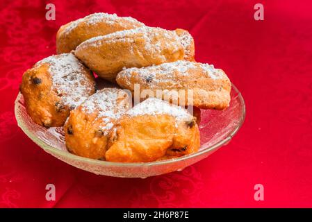 Traditioneller niederländischer Oliebollen und Appelflappen in einer Glasschale auf einer roten Tischdecke Stockfoto