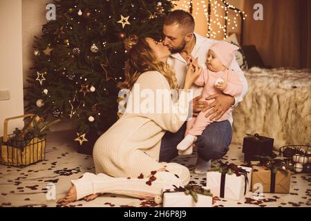 Küssen Eltern und Baby zu Weihnachten. Stockfoto